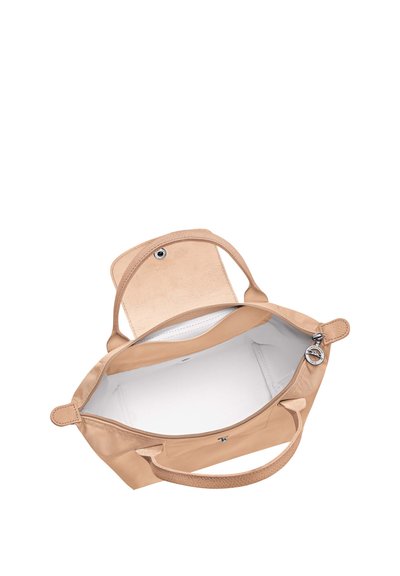 Beige handbag with two handles, open top flap, visible interior pocket, and round metal zipper pull with brand engraving.