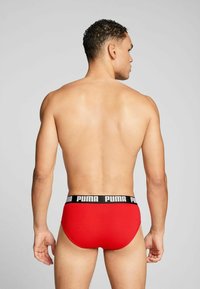 Rote Herrenunterhosen mit schwarzem elastischem Bund, der mit weißem "PUMA"-Branding versehen ist; glattes Material, enganliegendes Design und minimalistischen Stil.