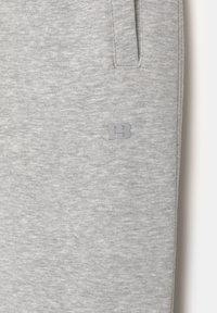 Helle graue Sweatpants aus weichem Stoff, mit einem tonalen Logo "PB" an der unteren Seite, seitlichen Taschen und einem entspannten Schnitt.