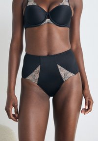High-waisted black panties featuring sheer lace side panels and a smooth finish. The design includes geometric cutouts and a solid waistband.