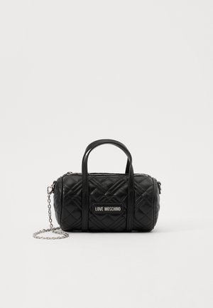Black quilted handbag with two top handles and a detachable chain strap. Features a branded plaque on the front and a zip closure.