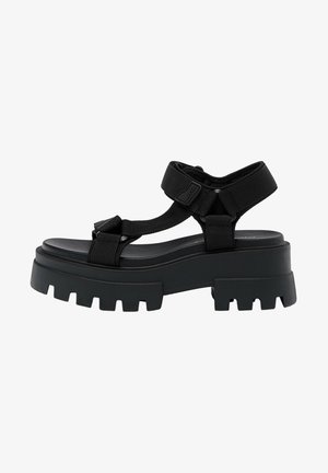 Sandalias negras de plataforma gruesa con tiras anchas, hebillas ajustables y suela texturizada con ranuras profundas para mejorar la tracción.