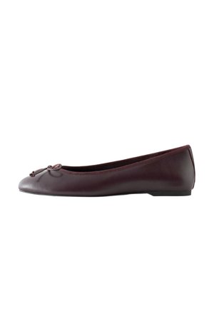 Ballerine plate en cuir violet foncé avec un petit nœud sur le bout arrondi et un talon bas et plat sur fond blanc.