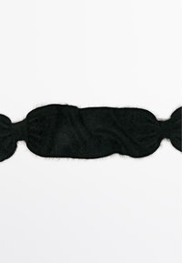 Bande en tissu noir et flou avec un design ondulé, s'étendant en ligne droite ; deux extrémités arrondies, texture douce et aucune quincaillerie visible.