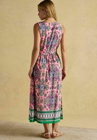 Rosa, blumenmuster Maxi-Kleid mit tailliertem Oberteil und schwingendem Rock. Besitzt filigrane Designs in Blau, Grün und Lila. Verstellbare Träger.