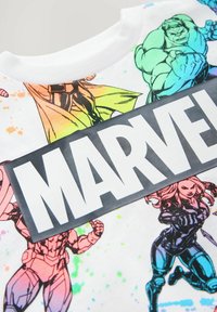 Witte katoenen t-shirt met kleurrijke stripstijl personages en een zwart "MARVEL" logo over de voorkant. Het ontwerp omvat spatten in verschillende kleuren.