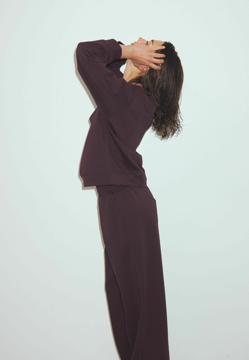 Brun loungewear sæt bestående af en afslappet sweatshirt og tapered bukser, lavet af blødt stof med en glat tekstur.