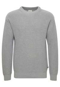 Harmaa neulepaita, jossa on pyöreä kaula-aukko, pitkät hihat ja ribbauskut. Tässä neulepaidan pinnassa on teksturoitu kuviokudos ja pieni etiketti helmassa.