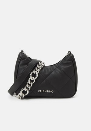 Sort quiltet Valentino skuldertaske med sølvkæde og sølvlogo foran på ensartet lys grå baggrund.
