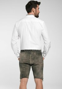 Weißes Langarmhemd kombiniert mit graubraunen Shorts. Die Shorts verfügen über seitliche Taschen und Knöpfe am Saum, mit einer strukturierten Stoffoptik.