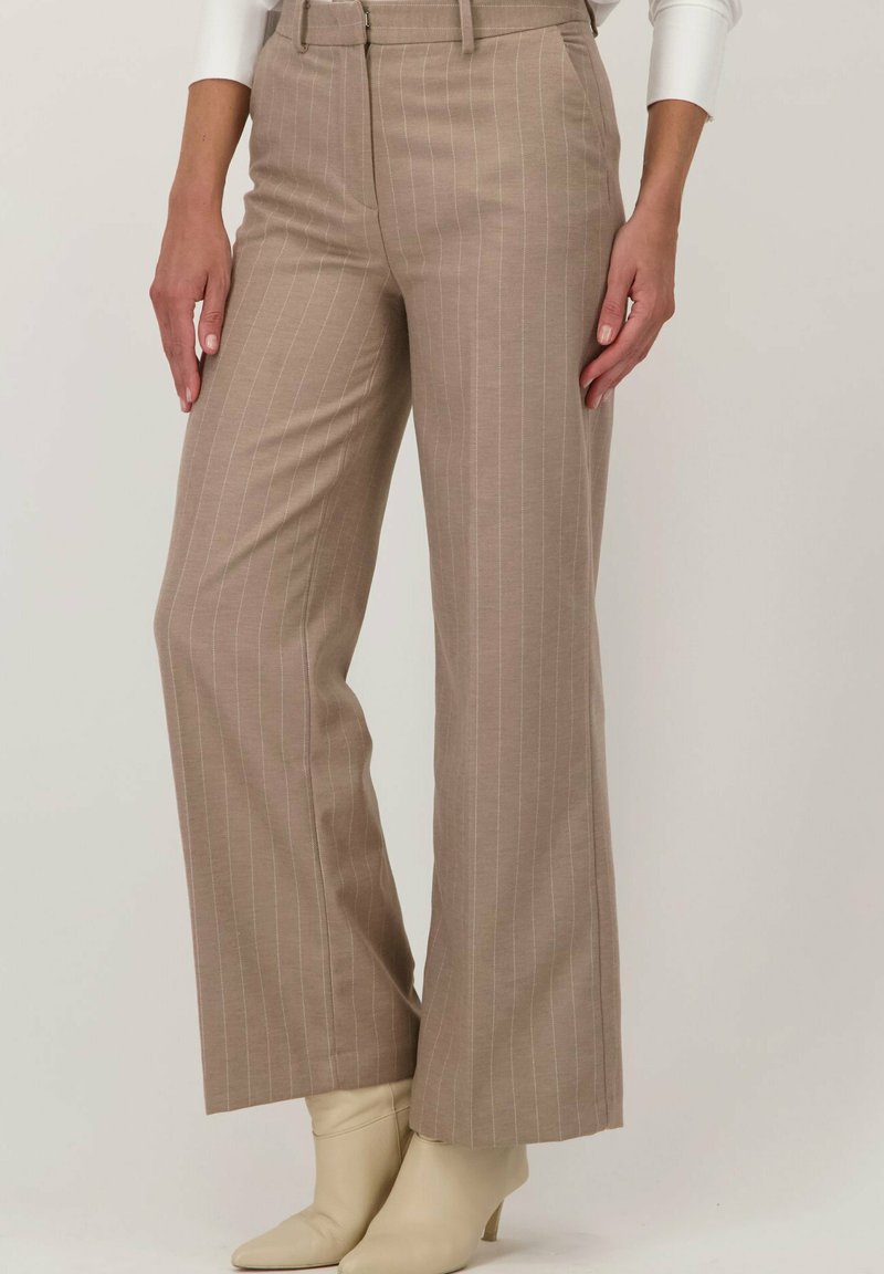 Beige pinstripe broek met een wijde pijp, hoge taille en een frisse textuur. Gecoördineerd met lichte, strakke enkellaarzen.