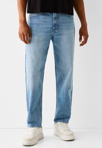 Jasnoniebieskie dżinsy z denimu o prostym kroju nogawki, z delikatnym blaknięciem i prześwietleniami, uzupełnione klasycznym układem pięciu kieszeni.