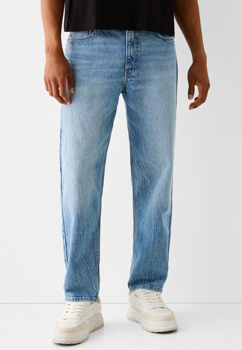 Jasnoniebieskie dżinsy z denimu o prostym kroju nogawki, z delikatnym blaknięciem i prześwietleniami, uzupełnione klasycznym układem pięciu kieszeni.