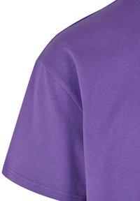 Tricou din bumbac violet cu mânecă scurtă, cu o textură netedă, decolteu rotund și margine de jos dretă, terminată.