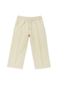 Pantalon beige court avec une taille élastique et un cordon blanc, doté de poches latérales et de détails de coutures à l'avant.