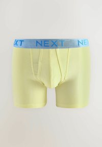 Sárga pamut boxeralsó, világoskék gumírozott derékkal, amin kék színnel a "NEXT" felirat látható. Puha tapintás és karcsú szabás.
