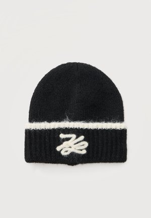 Bonnet en maille noir avec une bande blanche horizontale près du bord et un motif abstrait brodé blanc au centre avant.