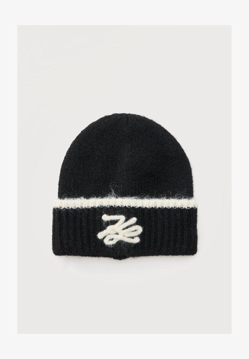 Bonnet en maille noir avec une bande blanche horizontale près du bord et un motif abstrait brodé blanc au centre avant.