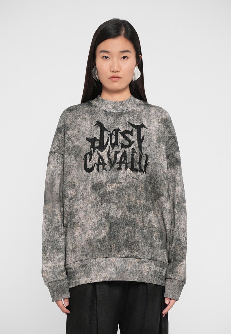 Sweatshirt cinza de grande tamanho com um acabamento texturizado, apresentando um proeminente logótipo preto "Just Cavalli" em letras bold na parte da frente.