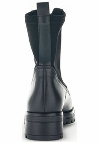 Zwarte enkelboots met een bovenwerk van leer en stof, ronde neus, een trekband aan de achterkant en een robuuste zool voor grip.