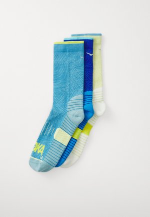 Trois paires de chaussettes de cheville dans des nuances variées de bleu, vert et blanc. Présente des motifs, des rayures et des logos dans des couleurs vives.