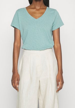 Lys teal v-hals t-shirt i blødt stof, kortærmet, parret med beige viddebukser. Simpel, afslappet design uden mønstre.