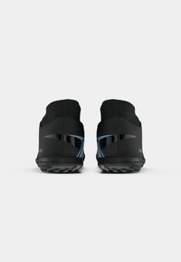 Scarpe da ginnastica nere con un design aerodinamico, suole testurizzate e dettagli blu sui lati laterali. Senza lacci visibili; stile slip-on.