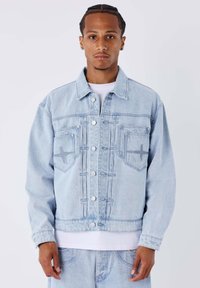 Giacca in denim azzurro chiaro con taglio classico, caratterizzata da due tasche frontali, chiusure con bottoni e dettagli di cuciture sottili sul petto.