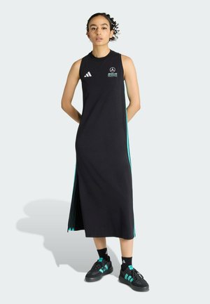 Robe noire sans manches avec fente latérale, ornée d'accents turquoise et d'un logo. Associée à des chaussures noires et des chaussettes avec des détails turquoise.