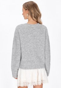 Grau, kuscheliger Pullover mit lockerer Passform, rundem Ausschnitt und langen Ärmeln, kombiniert mit einem cremefarbenen Rock mit Spitzenbesatz.