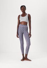 Grå kort sportbh och mönstrade leggings i marinblått med rosa accenter, som har geometriska mönster och ett stretchigt, figurnära tyg.