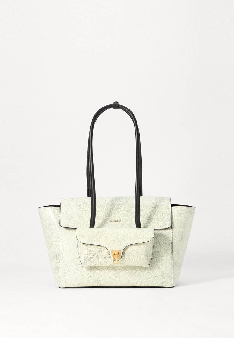 Bolso de cuero texturizado en color crema con acentos en negro, que cuenta con dos asas largas y un bolsillo frontal con solapa asegurado con un broche dorado.