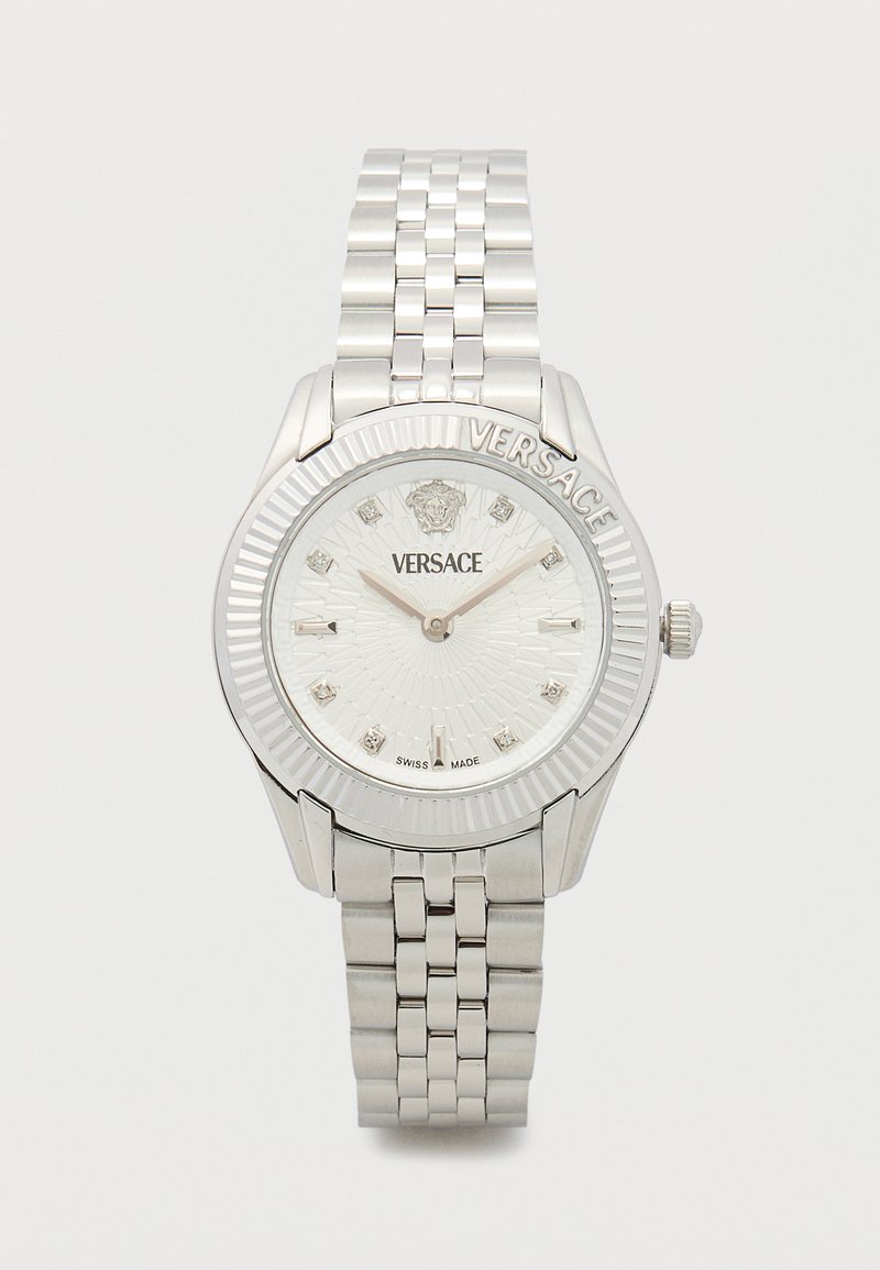 Hõbedane roostevabast terasest käekell tekstuurse valge sihverplaadiga, millel on teemantide sarnased märgised ja põimitud käevõru disain. Korpusel on graveeritud "VERSACE".