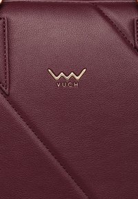 Burgunderfarbene Leder-Handtasche mit diagonaler Naht und goldfarbenem "VUCH"-Logo. Glatte Textur mit strukturiertem Design und minimalen Hardware-Akzenten.