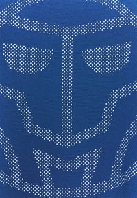 Modrá látka s velkým bílým puntíkovaným grafickým motivem připomínajícím stylizovanou masku nebo tvář s ostrými rysy a texturovaným pozadím.