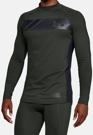 Man in een donkergroene lange mouwen atletische compressietop en bijpassende leggings met zwarte zijpanelen en een logo op de borst.