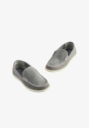 Scarpe slip-on in suede grigio con cuciture bianche e punta rotonda. Suola in gomma bassa per comfort e flessibilità.