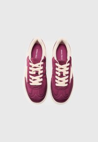 Baskets de sport violettes et crème avec une texture lisse, présentant des lacets ronds, des coutures en zigzag et une semelle en caoutchouc blanche.