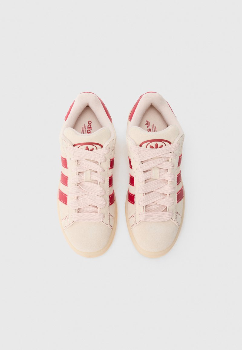 Zapatillas de ante rosa con rayas rojas, punta redonda, cierre con cordones y interior acolchado. Suela plana de goma. Logotipo icónico en la lengüeta.