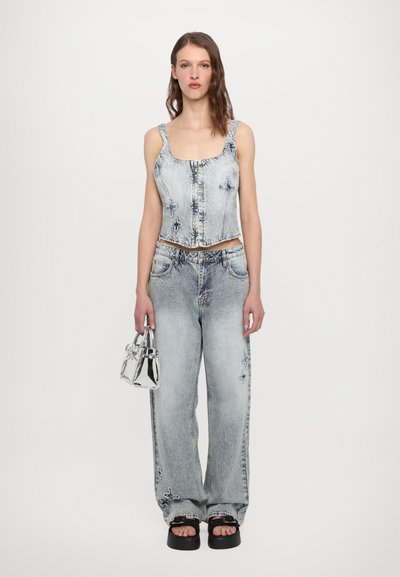 Denim cropped top with square neckline, distressed light wash, button closure. Wide-leg jeans in matching fabric. Silver mini handbag. Chunky sandals.