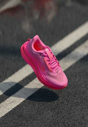 Bright pink athletic shoe with mesh upper, padded collar, and rubber sole. Features contrasting accents and a textured design.
