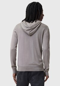 Felpa leggera grigia con un fit rilassato, maniche lunghe e cappuccio classico. Caratterizzata da polsini e orlo a coste, texture liscia e senza loghi visibili.