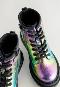 Bottines à lacets avec une finition métallique irisée, lacets noirs et semelle en caoutchouc texturé. Fermeture éclair sur le côté pour un enfilage facile.