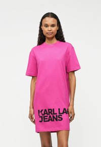 Vestido t-shirt oversized em algodão rosa com mangas curtas e decote redondo, apresentando um ousado texto em preto "KARL LAGERFELD JEANS" na frente.