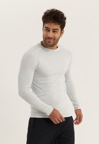 Helles graues langärmeliges Sportshirt aus glattem Stoff, mit strukturierten Punktmustern an den Schultern und Seiten, runder Ausschnitt.