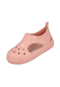 Zapato de goma rosa sin cordones con agujeros de ventilación, puntera redondeada y suela texturizada. Presenta una correa en la parte trasera y un logo de la marca en relieve.