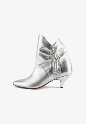 Zilveren metallic enkellaarsjes met een spitse neus, geplooide details aan de zijkant en een lage kittenheel. Gladde textuur, strakke vormgeving.