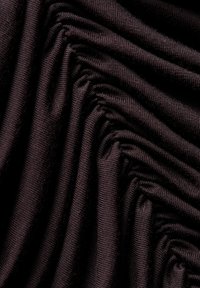 Czarna tkanina z serią teksturowanych fałd, ukazująca miękki, elastyczny materiał dzianinowy o subtelnym połysku.