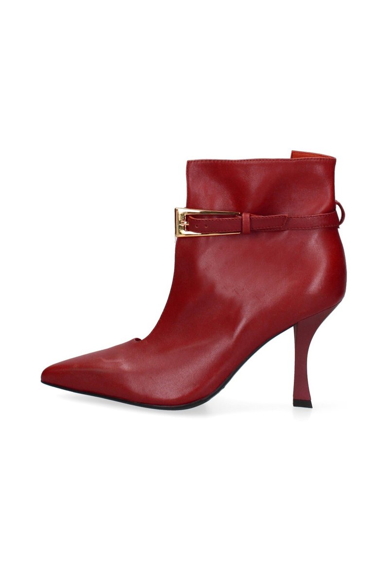 Stivaletto alla caviglia in pelle rossa con punta affilata, alto tacco a spillo e dettaglio a fibbia in tonalità oro su una larga fascia. Texture liscia, design elegante.