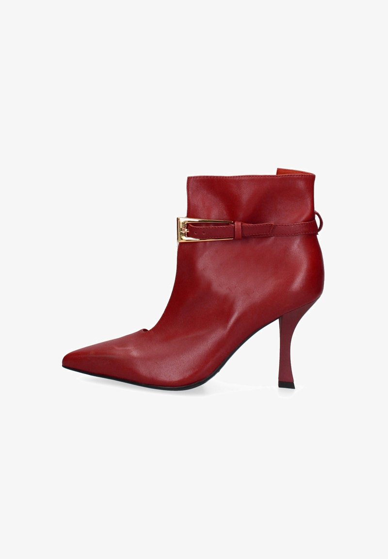 Stivaletto alla caviglia in pelle rossa con punta affilata, alto tacco a spillo e dettaglio a fibbia in tonalità oro su una larga fascia. Texture liscia, design elegante.